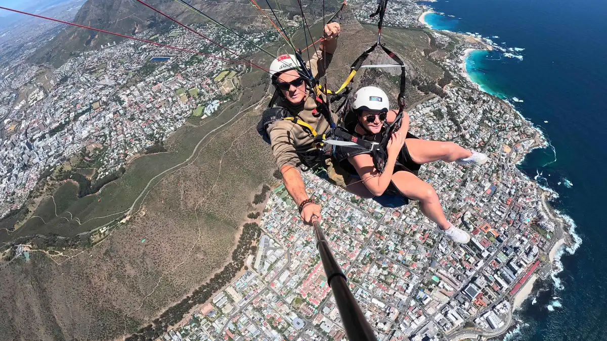 Paragliding pilot and passenger soaring with Table Mountain views on a tandem flight, Cape Town